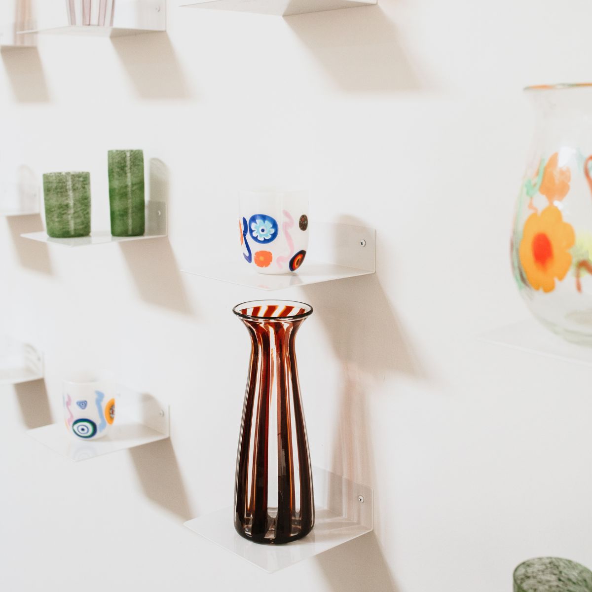 Wall in The Selby House studio with variety of hand blown laguna b glassware.