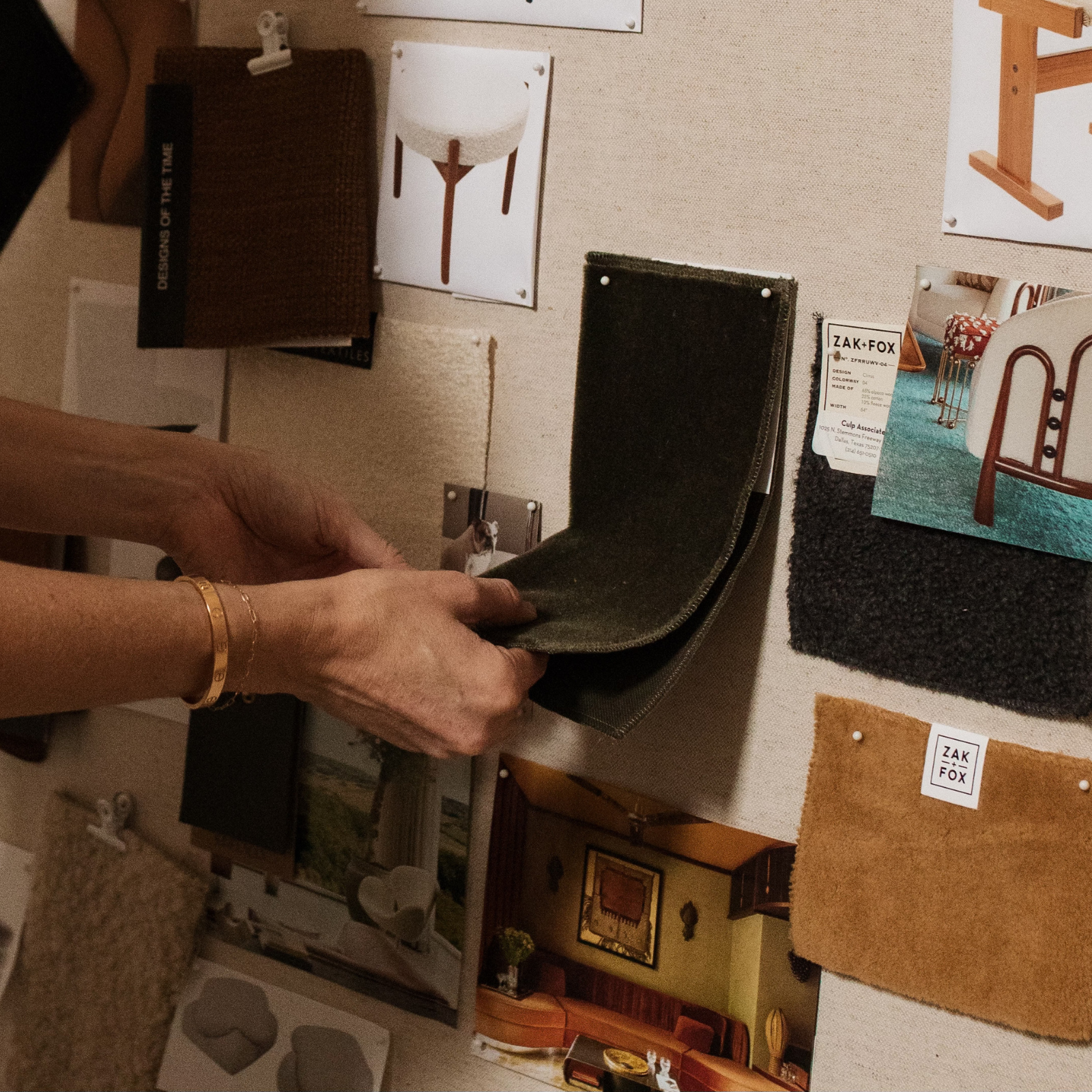 Hands feeling custom fabrics pinned on board showing custom furniture.