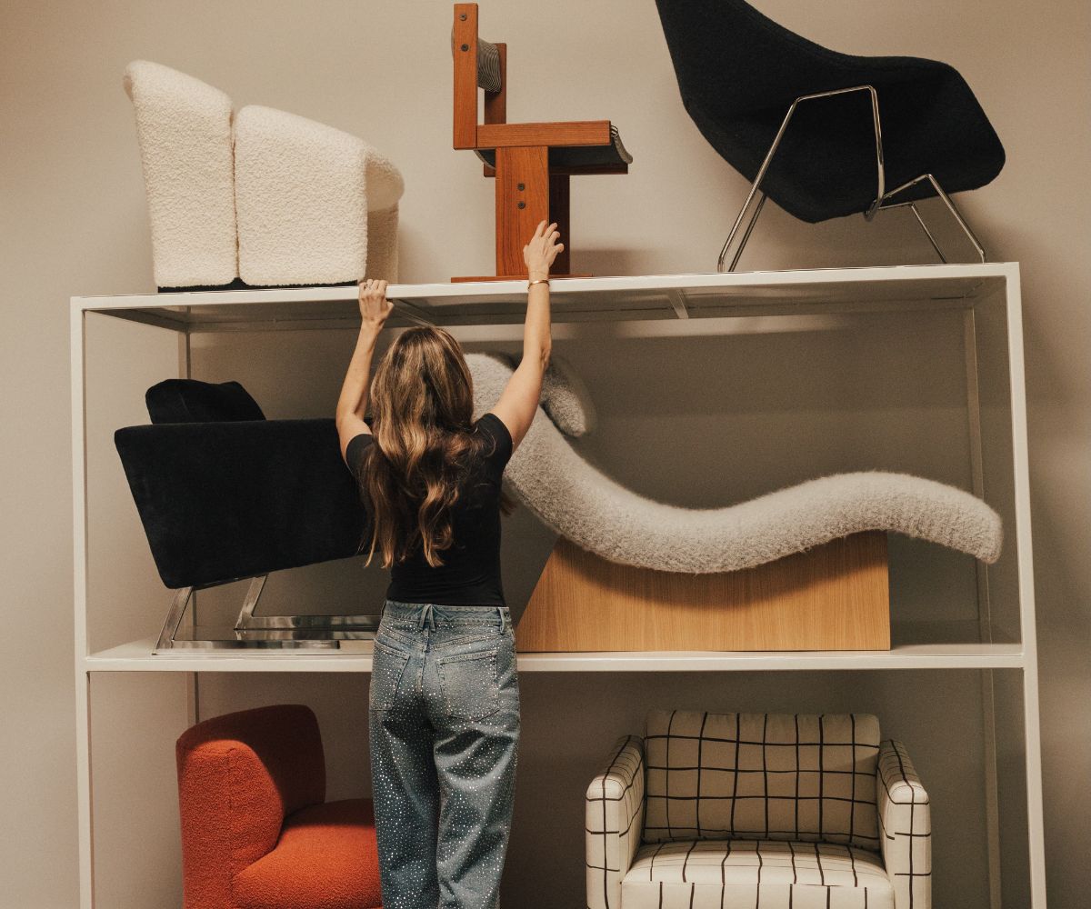 Woman reaching for rare vintage chair on top shelf.