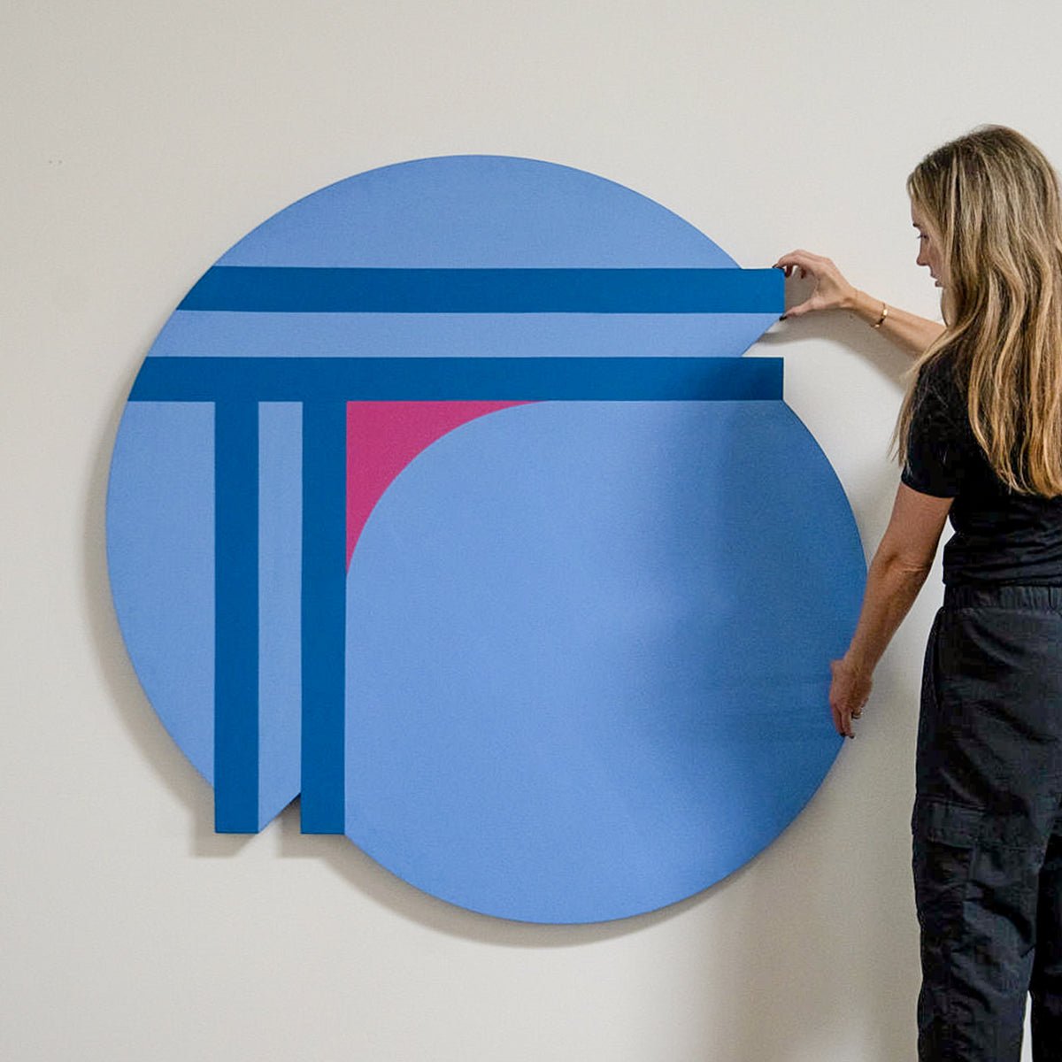 Large artwork on circular canvas with woman next to it.
