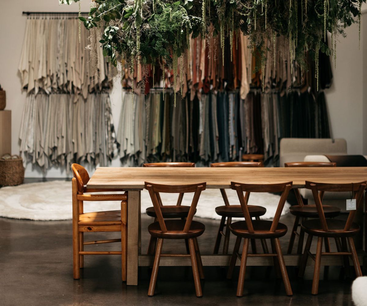 Inside The Selby House studio, a large wooden table and chairs with wall of custom fabrics behind it.